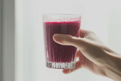 햇살 아래 건강한 베리 스무디를 들고 있는 모습