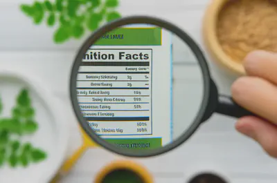 모링가 제품 라벨을 확대경으로 확인하는 모습