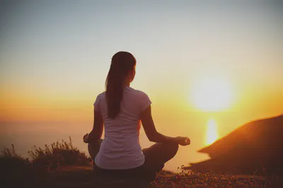 일출을 배경으로 명상하는 사람의 뒷모습