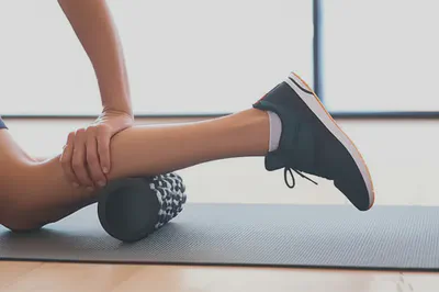 폼롤러를 사용하여 다리 근육을 마사지하는 모습