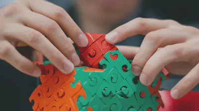 복잡한 3D 퍼즐을 집중해서 맞추는 손, 능동적인 인지 활동의 중요성.